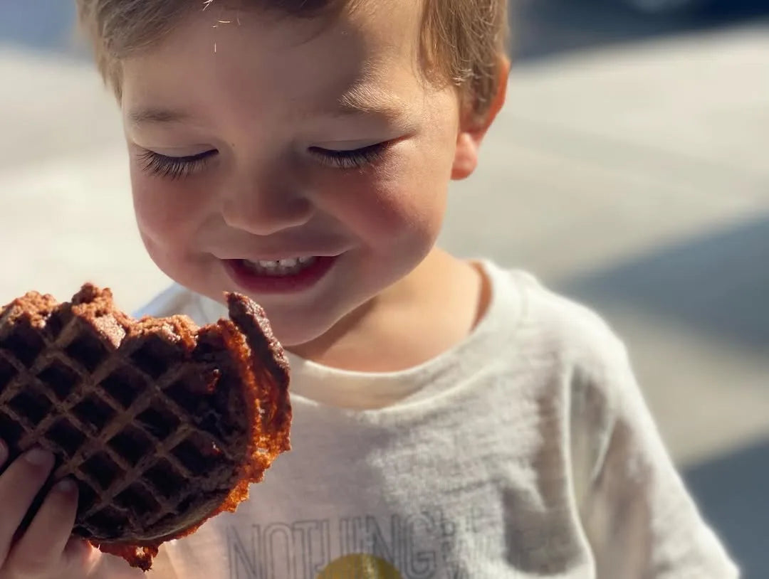 A child taking a big bite of a Chocolate Unwaffle